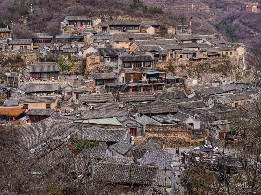 Traditional stone?built courtyard houses of Cuanxia ancient village against green mountain backdrop