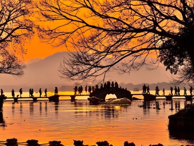 Silhouetted Visitors on West Lake Arch Bridge at Golden Sunset