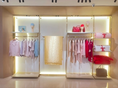 Silk pajamas, scarves and gift boxes displayed on illuminated shop shelves
