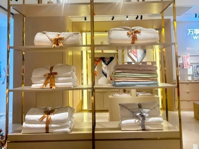 Folded silk bedding sets and pillows neatly arranged on display shelves