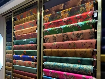 Large rolls of colorful traditional silk fabrics displayed in a fabric shop