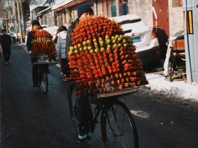 In winter, an elderly man sells candied hawthorns by bicycle in a Beijing hutong In winter, an elderly man sells candied hawthorns by bicycle in a Beijing hutong
