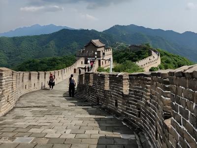Visitors walking along the Mutianyu Great Wall with watchtower and green mountains