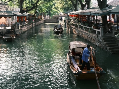 Wooden rowing boats sailing along canal, waterside shops and old buildings in Tongli water town Wooden rowing boats sailing along canal, waterside shops and old buildings in Tongli water town
